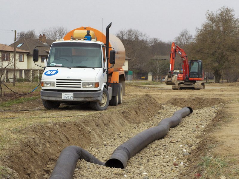 A vacuum truck beside an open septic drainfield trench